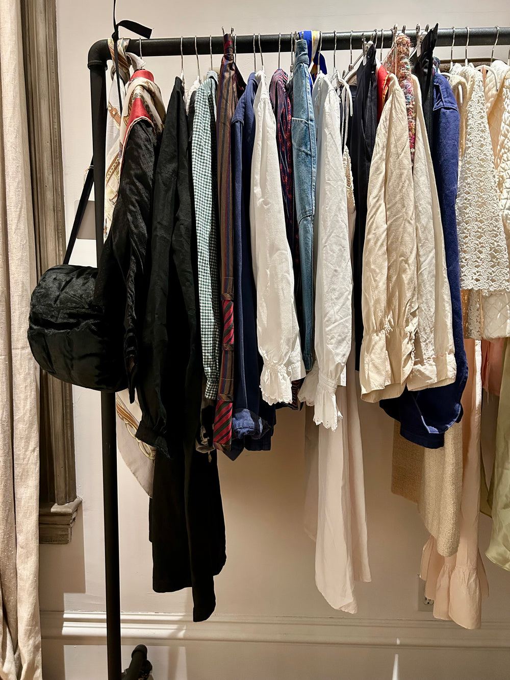 A rail of vintage blouses, workwear jackets, silk scarves and slips